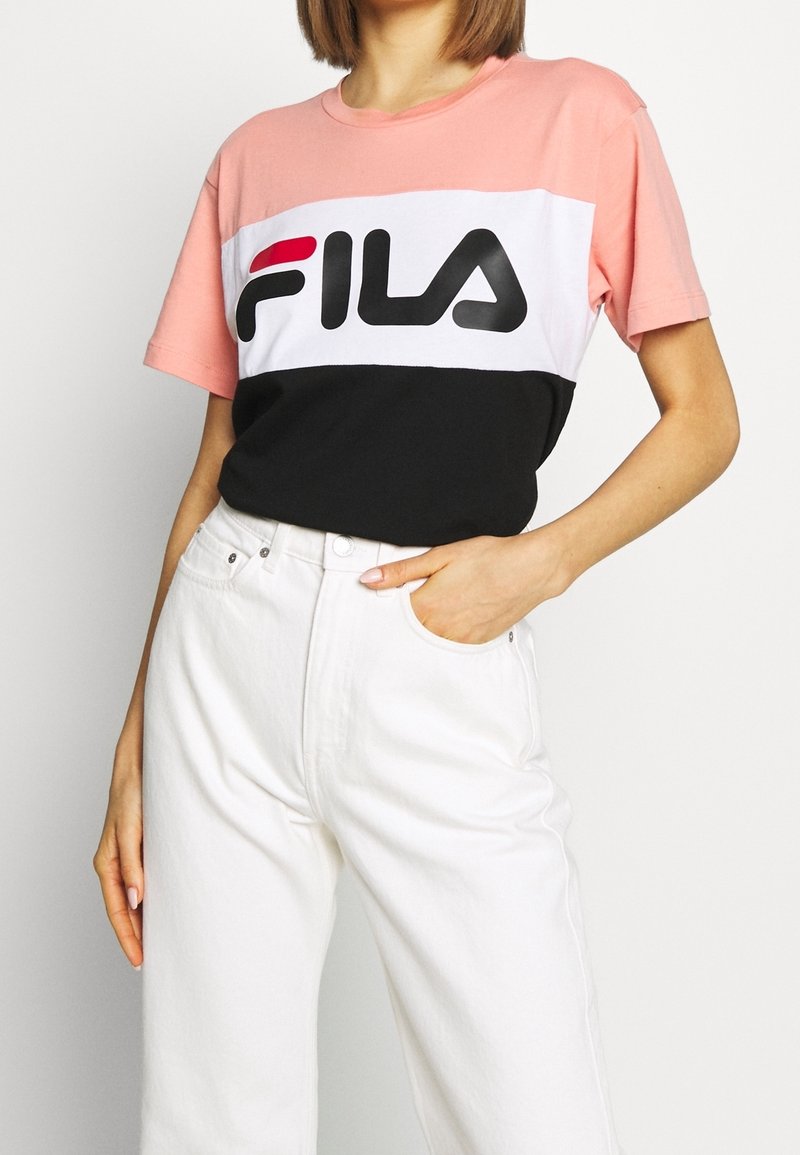Färgblock t-shirt med rosa, vit och svart sektioner. Stort "FILA"-logotyp i svart och rött. Korta ärmar, avslappnad passform.