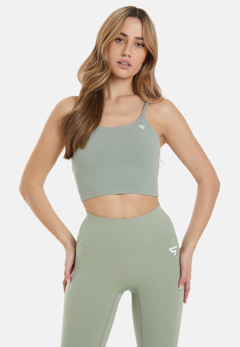 Lys grøn sport crop top med tynde stropper og et logo. Båret med matchende højtaljede leggings med en sømløs design.