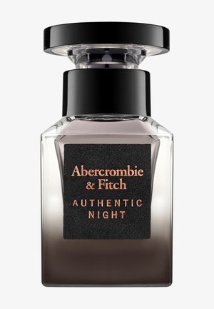 Flacon de parfum en verre transparent avec un bouchon noir et une étiquette portant l'inscription "Abercrombie & Fitch Authentic Night" en texte de couleur cuivre.