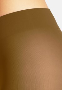 Collant marroni trasparenti con una texture a coste e una vita liscia, che mostrano una leggera lucentezza e una colorazione uniforme.