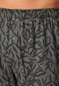 Boxershorts aus weichem Stoff mit einem dunkelgrauen Hintergrund und einem schwarzen Blattmuster, elastischem Bund und einem Knopfdetail vorne.
