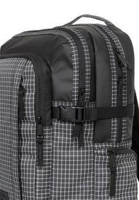 Zaino in nero e grigio, con un motivo a griglia, diversi scomparti con zip, fibbie in plastica durevoli e spallacci imbottiti.