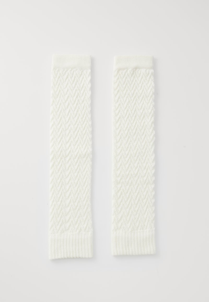 Een paar witte gebreide beenwarmers met een chevronpatroon en ribbels aan de mouwen, op een witte achtergrond.