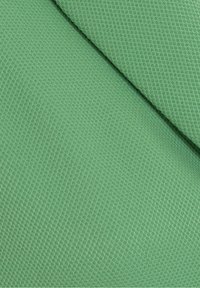 Gros plan d’un tissu vert texturé avec un petit motif géométrique et un pli diagonal sur la surface.