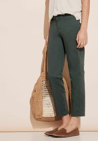 Mörkgröna skräddarsydda byxor i bomull, med slim fit och kortad längd. Styling med en vävd stråväska och bruna slip-on skor.