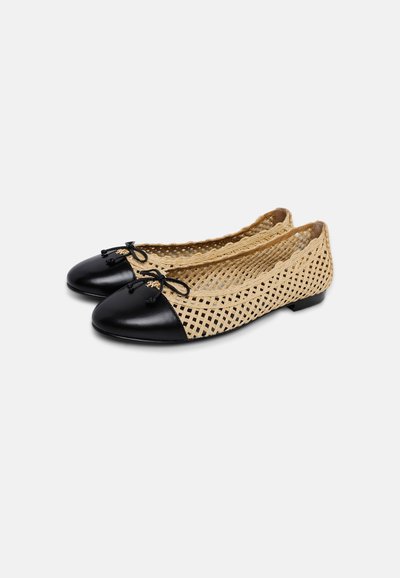 Paire de chaussures plates tissées beige avec bouts ronds noirs et petits nœuds noirs sur fond blanc.