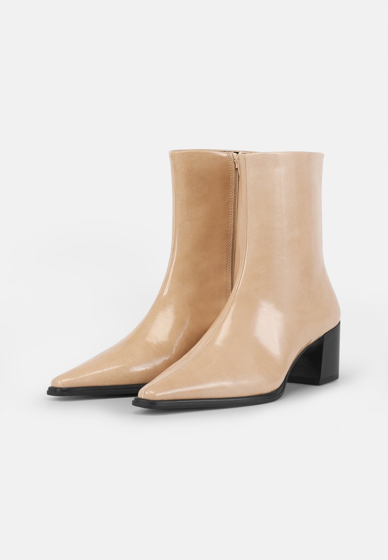 Beige leren enkellaarsjes met een glanzende afwerking, spitse neus, middellange blokhak en een zijrits voor gemakkelijke instap.