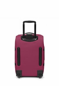 Rosa rullväska med hårt skal, utdragbart svart handtag och fyra svarta hjul. Har robusta svarta detaljer på sidorna.