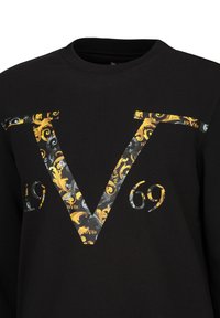 Schwarzer Sweatshirt mit einem großen, kunstvoll gemusterten "V" in Gelb, Grau und Weiß, das "1969" in das Design integriert.