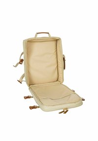 Zaino da viaggio beige con un ampio interno aperto e tasca in rete. Presenta dettagli in pelle marrone e chiusure con cerniera. Incluse spalline regolabili.
