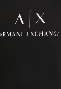Schwarzes Baumwoll-T-Shirt mit auffälligem weißen Text: "A/X ARMANI EXCHANGE." Einfaches Design, kurze Ärmel, glatte Textur.