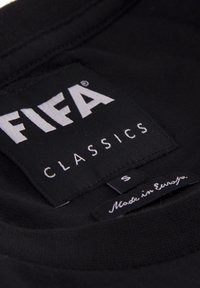 Zwarte katoenen t-shirt label met "FIFA CLASSICS" in witte tekst, maat "S", en "Made in Europe" in cursief op een label van stof.