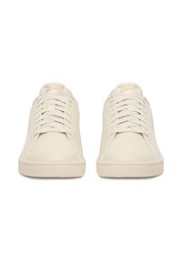 Pár krémovo sfarbených tenisiek Reebok so šnúrkami, zobrazených spredu na bielom pozadí.