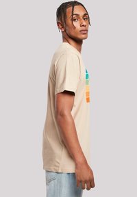 Beige short-sleeve t-shirt featuring a multicolored geometric print on the front. Made of soft cotton with a relaxed fit.