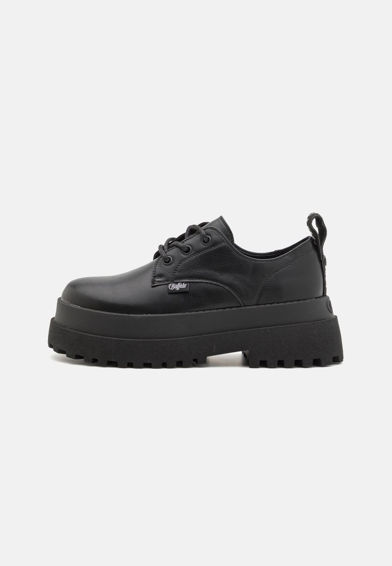 Chaussure plateforme en cuir noir avec semelle crantée épaisse, laçage à l'avant, étiquette de marque sur le côté et languette de traction au talon sur fond blanc uni.