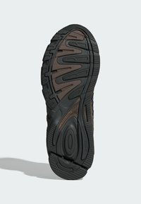 Must must sneakeri kummiga mustal põhjal, millel on tekstuurigaastmik ja pruun aktsent. Omab sooni ja sälke, et tagada haakumine ning tugi.