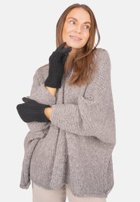 Grau, strukturiertes Sweatshirt mit lockerer Passform und weiten Ärmeln, kombiniert mit schwarzen, gerippten Handschuhen. Fokus auf dem gemütlichen Stoff und den kontrastierenden Farben.