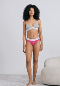 Sivé podprsenkové braletky a ružové tangá s bielymi elastickými pásikmi, s logom Calvin Klein. Hladká tkanina, jednoduchý dizajn.
