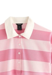 Polo a righe rosa e bianche con colletto a contrasto, caratterizzato da una patta con cinque bottoni e una morbida texture del tessuto. Etichetta del marchio visibile.