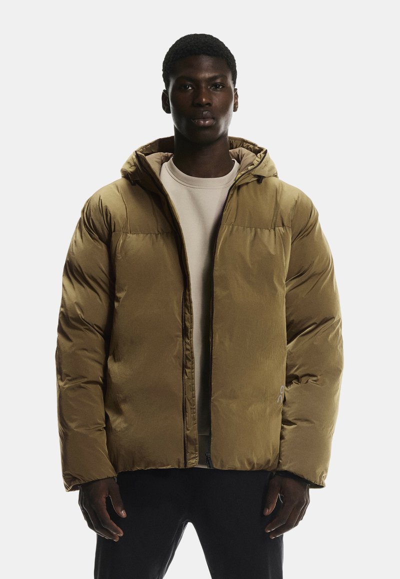 Dicke Jacke in einem gedämpften Olivgrün, mit Kapuze, Reißverschluss und gerippten Bündchen. Glatte Außenfläche mit minimaler Markenpräsenz.