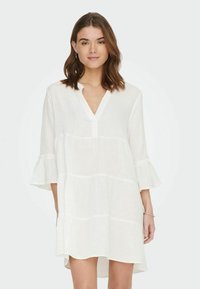 Weißes Leinenkleid mit Dreiviertelärmeln, Ausschnitt und ausgestellten Manschetten. Verfügt über ein strukturiertes Muster und eine lockere Passform.