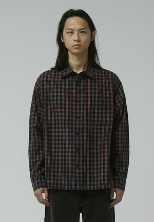 Checkered button-up shirt in dark navy and red pattern, featuring a spread collar, long sleeves, and a relaxed fit. Cotton material.