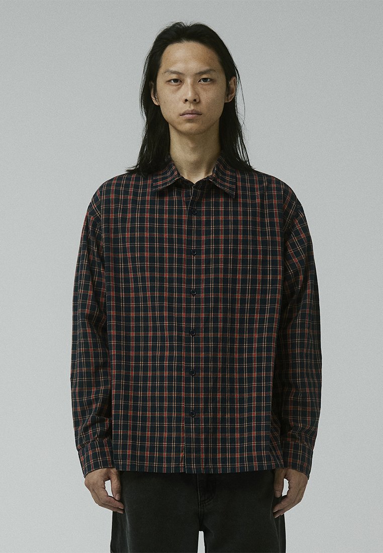 Checkered button-up shirt in dark navy and red pattern, featuring a spread collar, long sleeves, and a relaxed fit. Cotton material.