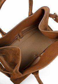 Brown suede handbag with beige fabric interior, featuring an inner zip pocket, a small clasp, and two handles.