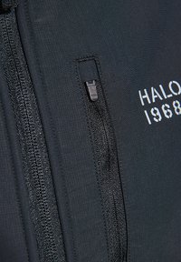 Schwarze Jacke mit strukturiertem Stoff, zwei Reißverschlusstaschen und "HALO 1968"-Logo in weißer Schrift. Das Design umfasst detaillierte Nähte.
