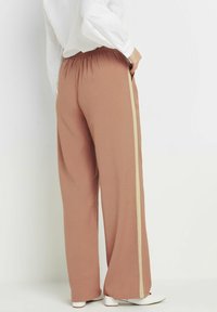 Brede-pijp broeken in een stoffige rozenkleur, met een elastische tailleband en een contrasterende beige zijstreep. Zacht stof met een gladde textuur.