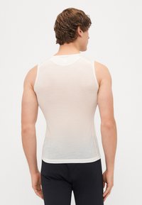 Fehér tank top hálós textúrával, kerek nyakkivágással és ujjatlan kivitelben. Az alja diszkrét díszítéssel van befejezve.