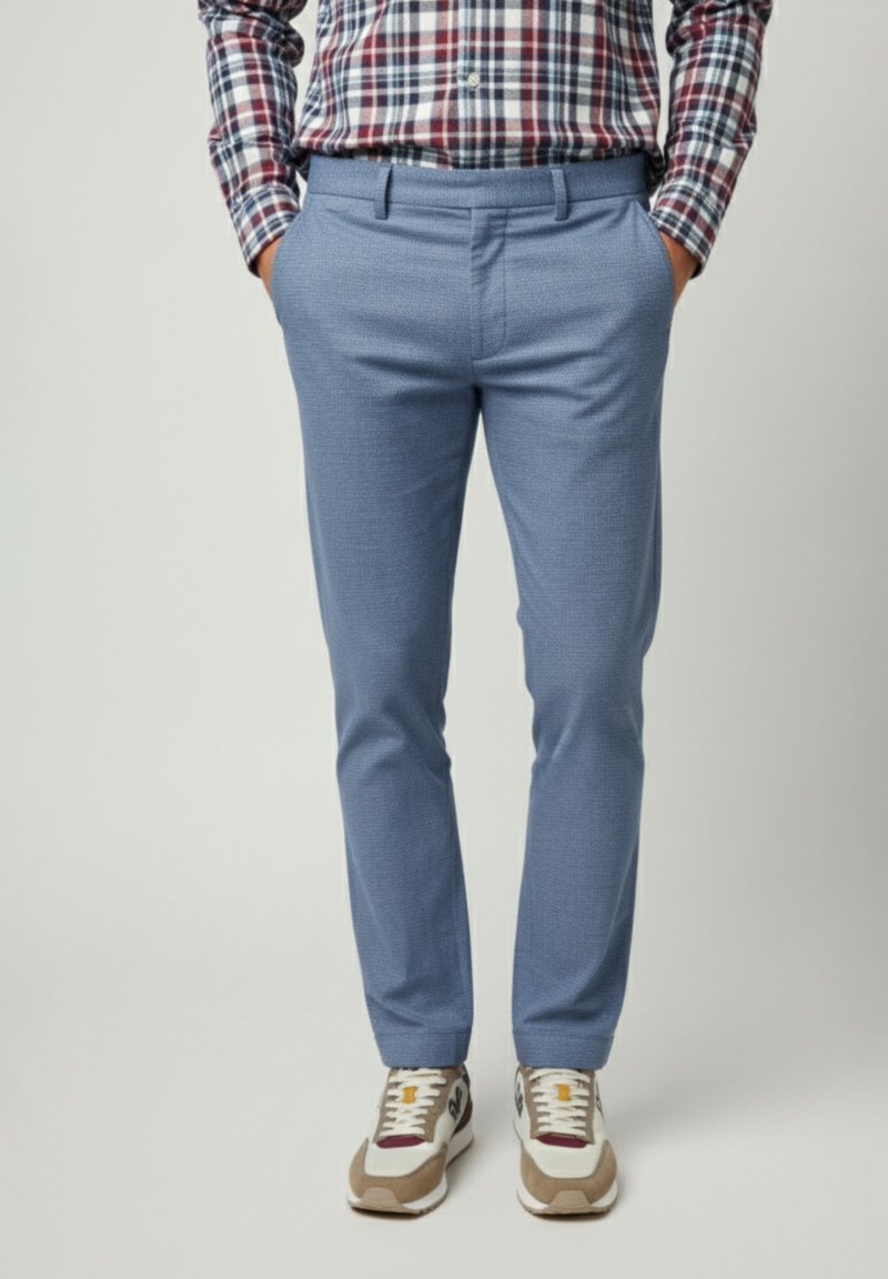 Pantalones azules claros a medida con un acabado texturizado, que cuentan con bolsillos laterales y un corte slim. Combinados con zapatillas grises y beige.