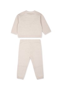 Completo in maglia a due pezzi di colore beige chiaro, composto da un top a maniche lunghe con un motivo testurizzato e pantaloni aderenti abbinati con polsini a coste.