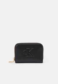 Black leather wallet with raised "cK" logo, gold zipper accent, rectangular shape, smooth texture, compact design.