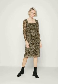 Vestido com padrão de leopardo, feito de tecido transparente, com mangas longas, decote quadrado e silhueta ajustada, combinado com botas pretas de cano curto.