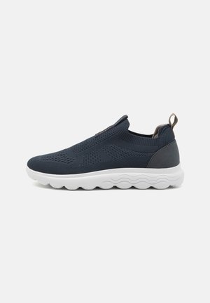 Granatowe sneakersy slip-on z teksturowaną dzianiną na cholewce, białą, amortyzującą podeszwą i szarymi akcentami na pięcie. Lekka i oddychająca konstrukcja.