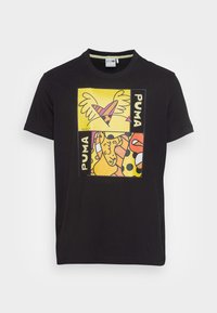 Sort kortærmet T-shirt med farverige grafiske prints, der har gule baggrunde, hjerter og abstrakte mønstre; lavet af bomuld.
