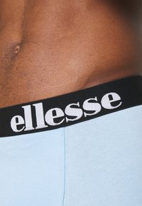 Ljusblå underkläder med en elastisk svart midjeband som har vit "ellesse"-logotyp. Slät textur med en åtsittande passform.