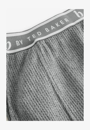 Harmaa neulotun kankaan vyötäröosa, jossa on teksturoitu kuvio ja kontrastivärinen vaaleanharmaa raita, jossa on painettu valkoisella "by TED BAKER".