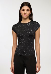 Czarny krótki top z krótkim rękawem i okrągłym dekoltem, zdobiony rozsianymi srebrnymi ćwiekami, wykonany z gładkiego materiału o dopasowanym kroju.