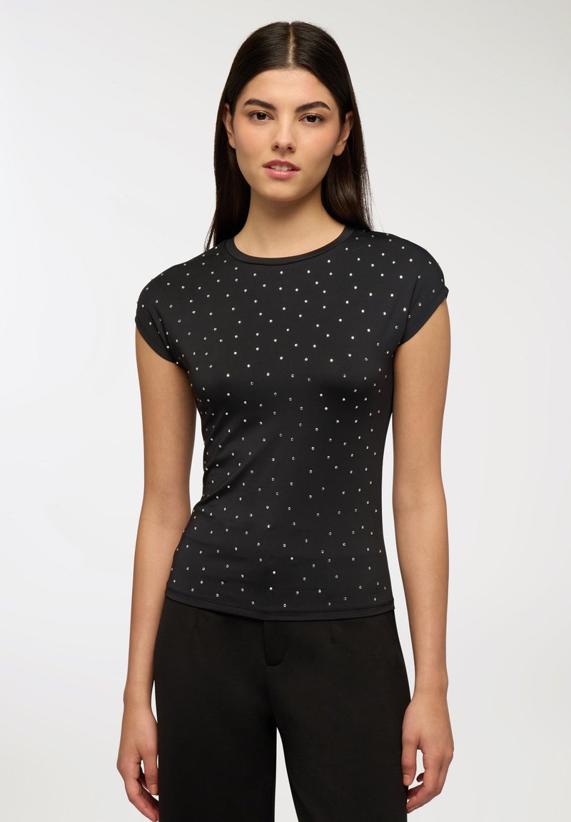 Czarny krótki top z krótkim rękawem i okrągłym dekoltem, zdobiony rozsianymi srebrnymi ćwiekami, wykonany z gładkiego materiału o dopasowanym kroju.