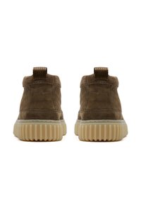 Stivaletti in suede marrone con suola in gomma rigata e linguetta testurizzata. Presentano una punta arrotondata e cuciture rinforzate lungo le giunture.