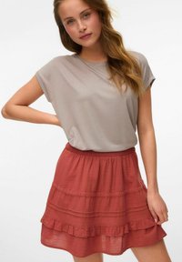 Camiseta gris de manga corta y falda acampanada color óxido con dobladillo con volantes y cintura elástica. Tela suave con patrones texturizados.