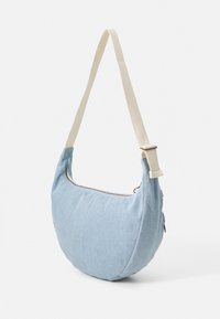 Borsa a spalla in denim azzurro chiaro con tracolla regolabile crema e chiusura a cerniera. Forma arrotondata con dettagli di cuciture minime.