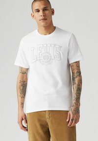 Vit bomull t-shirt med en stor grå Levi's-logotyp på bröstet, kompletterad med korta ärmar och rundad halsringning.