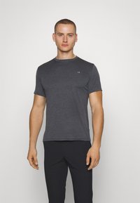 Dark gray crew neck t-shirt made of soft fabric, featuring short sleeves and a subtle logo on the chest, paired with black pants.