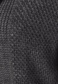 Mörkgrått stickat tyg med en tät, mönstrad väv och synliga garn detaljer. Vävd i ett tätt, kompakt mönster för hållbarhet.