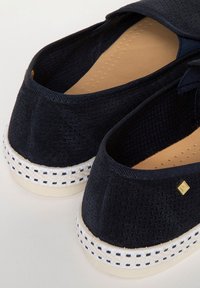 Espadrilles navy en tissu texturé avec col élastique, semelle intérieure beige et semelle tissée blanche avec accents noirs.