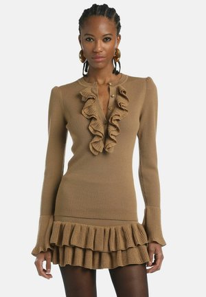 Brown ribbed dress with long sleeves, ruffled front detail, and flared hem. Made from textured fabric, featuring button closure at neckline.