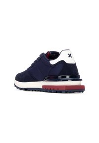 Zapatilla marina que presenta una combinación de tejido suave y ante, talón blanco, suela roja y marina, y una entresuela texturizada.